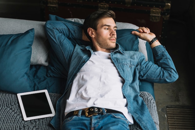 Handsome young man lying on bed holding the pillow with hand