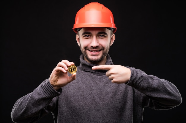 Foto gratuita il minatore del giovane bello in hemlet protettivo ha indicato su bitcoin isolato sul nero