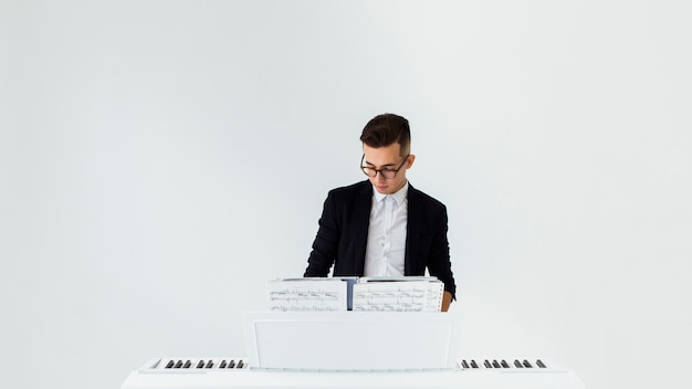 Free photo handsome young man playing the piano against white background