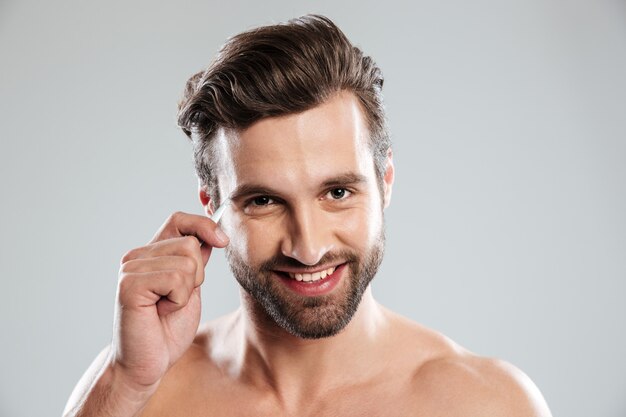 Handsome young man plucking his eyebrows with tweezers