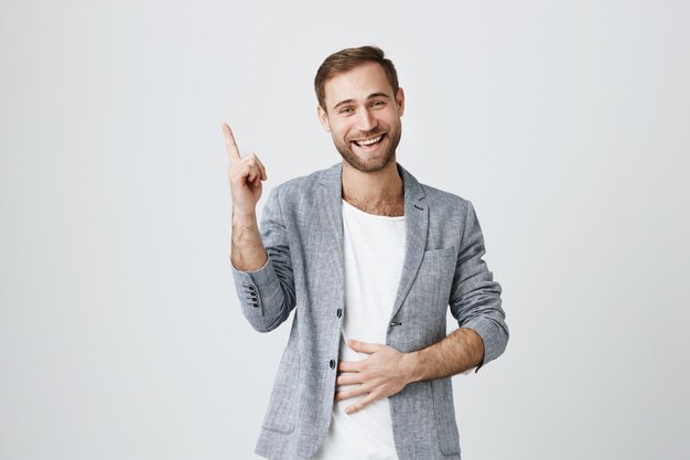 Handsome young man pointing finger up at advertisement