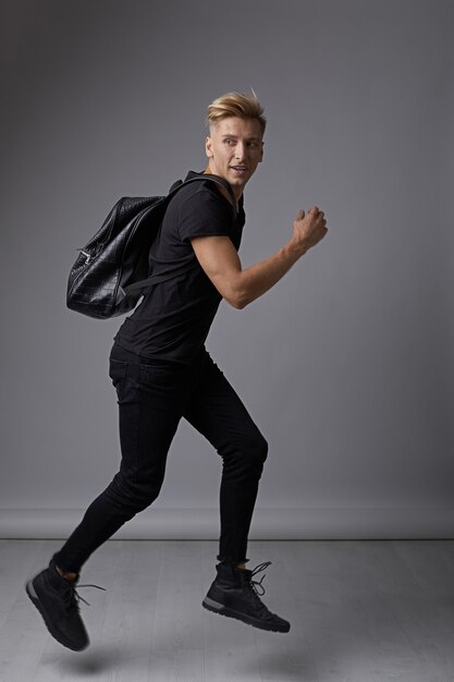 Handsome young man running with a backpack on shoulders