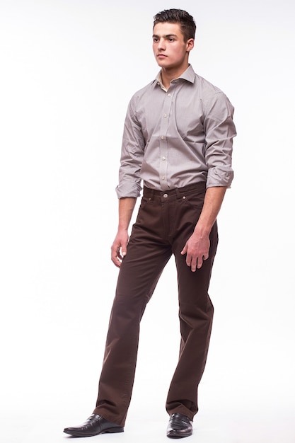 Handsome young man in shirt while standing against white wall