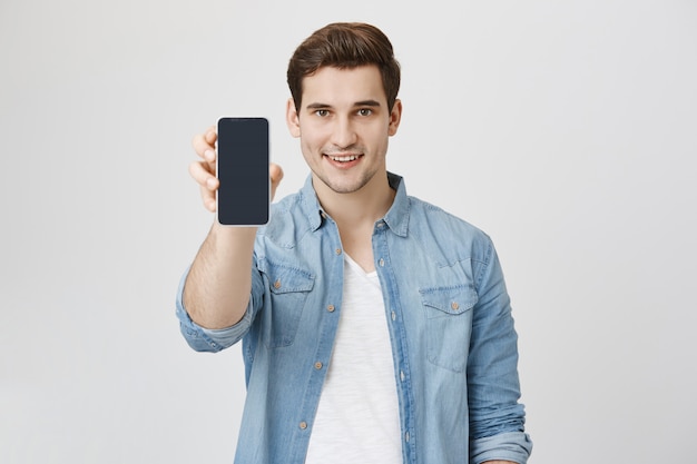 Handsome young man showing smartphone application