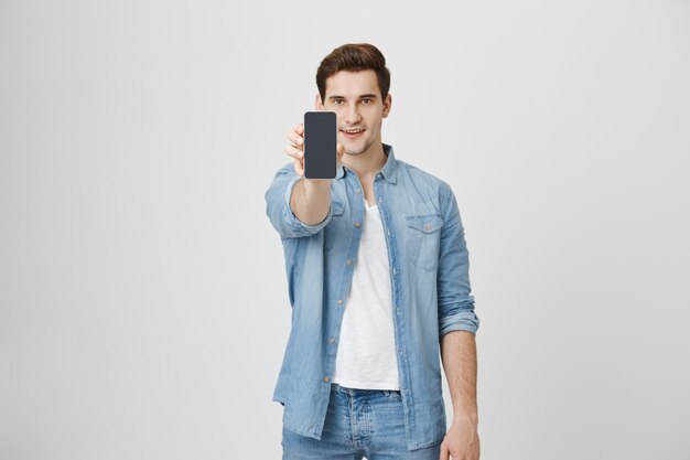 Handsome young man showing smartphone