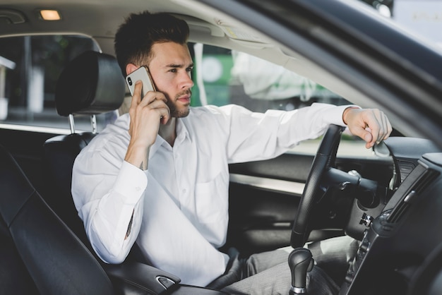 無料写真 携帯電話で話す車に座っている幸せな若い男