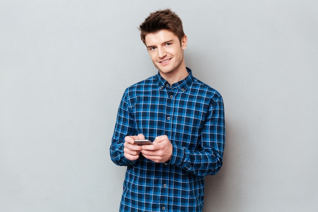 Handsome young man standing over grey wall and chatting