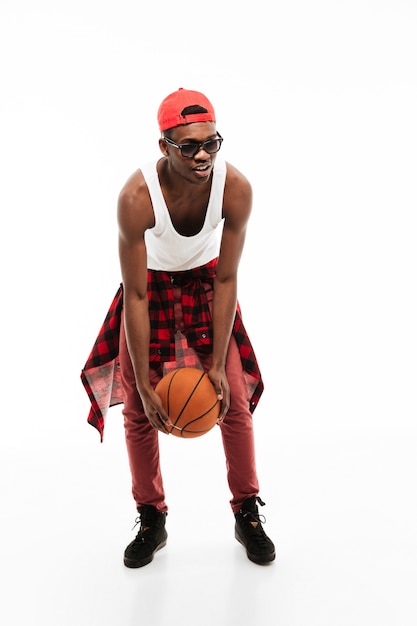 Free photo handsome young man standing and playing with basketball ball