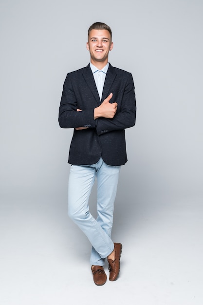 Handsome young man student businessman in jacket holds his arms crossed isolated on light grey wall