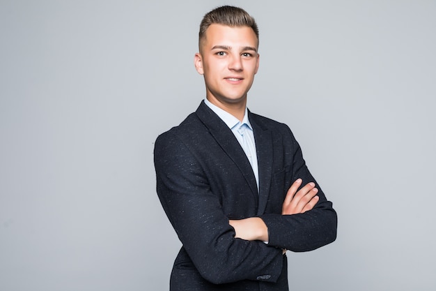 Handsome young man student businessman in jacket holds his arms crossed isolated on light grey wall