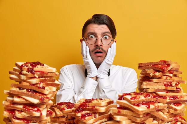 Handsome young man surrounded by peanut butter jellly sandwiches