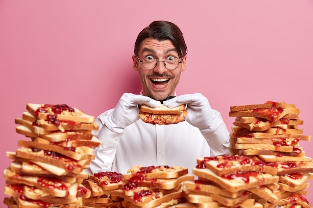 Free photo handsome young man surrounded by peanut butter jellly sandwiches