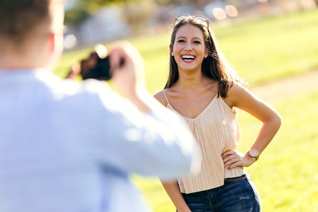 Handsome young man taking photo of his girlfriend in the park