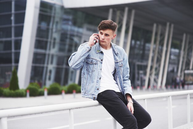 A handsome young man talking on the phone near the office space.