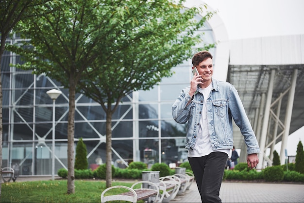 A handsome young man talking on the phone near the office space.