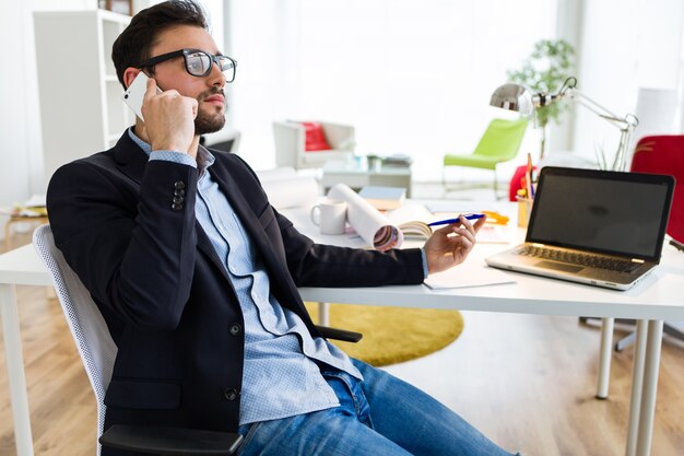 Handsome young man using his mobile phone in the office.