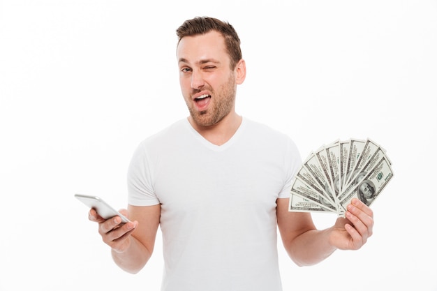 Handsome young man using mobile phone holding money.