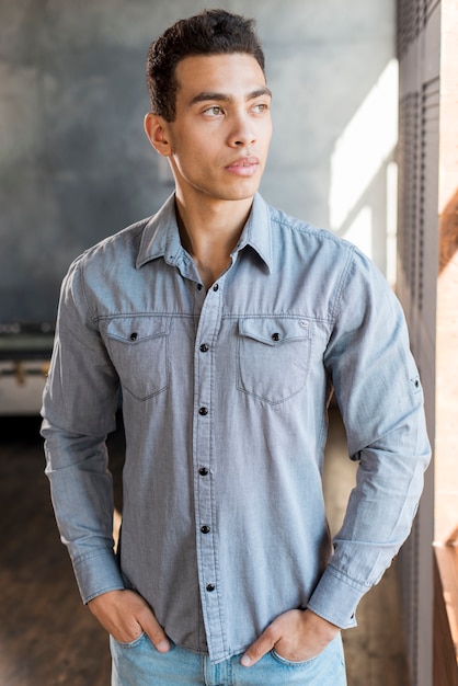 Handsome young man with his hands in pocket looking away