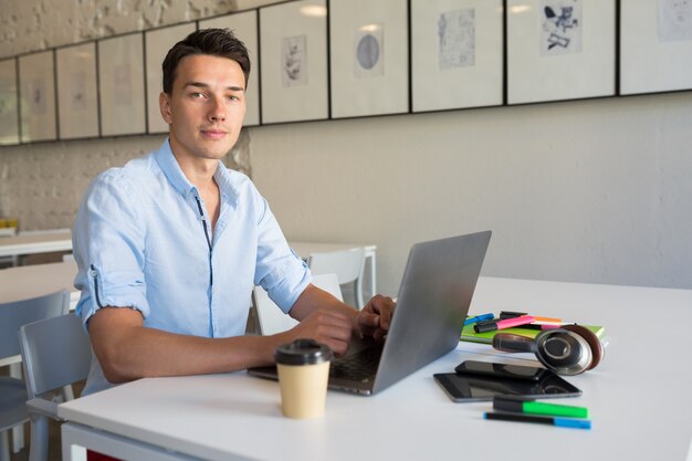 Handsome young man working on laptop, typing, freelance job online