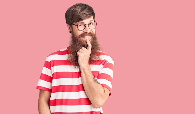 Free photo handsome young red head man with long beard wearing casual clothes looking confident at the camera with smile with crossed arms and hand raised on chin thinking positive