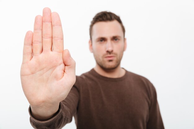 Handsome young serious man showing stop gesture.