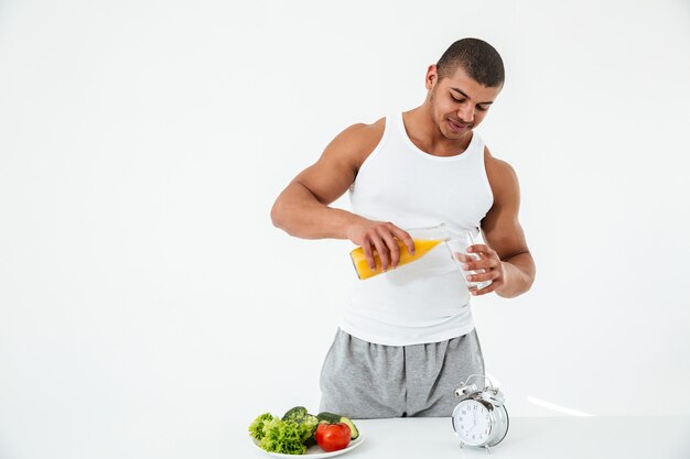 handsome young sportsman holding glass of juice.