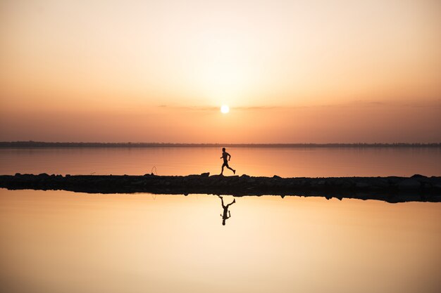 Handsome young sportsman running at the beach