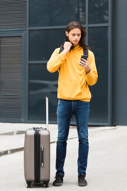 Красивый молодой путешественник проверяет свой телефон