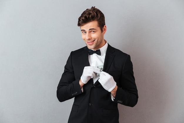 Handsome young waiter while holding money.