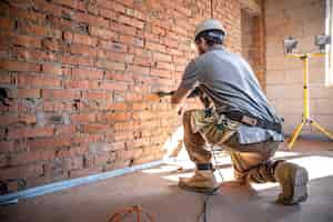 Foto gratuita tuttofare in un cantiere in procinto di perforare un muro con un perforatore