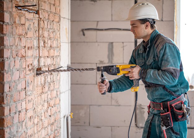 Handyman in the process of drilling a wall with a perforator.