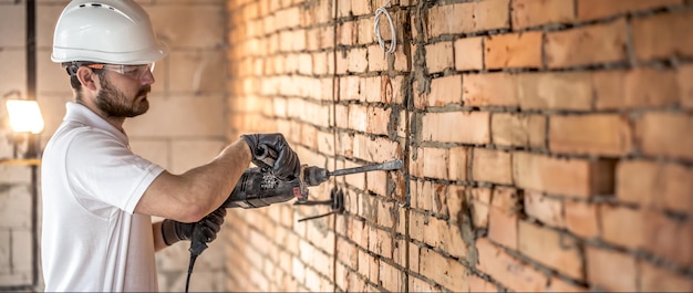 Foto gratuita un artigiano che sta perforando un muro con un perforatore