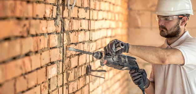 Foto gratuita un artigiano che sta perforando un muro con un perforatore