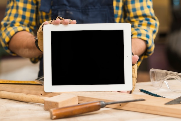 Handyman showing digital tablet with blank screen on workbench