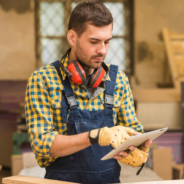 A handyman using digital tablet in the workshop