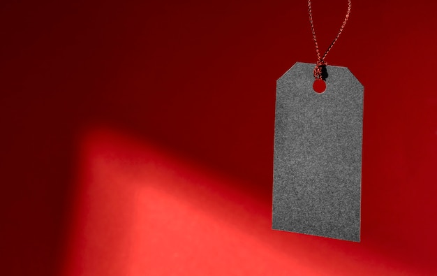 Hanging black price tag on red background copy space