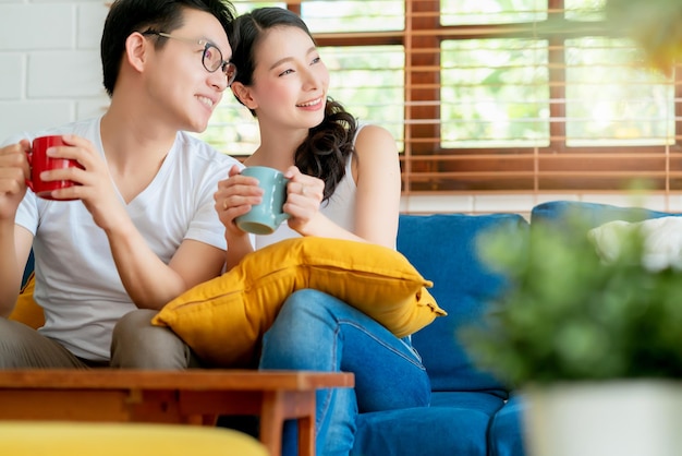 La famiglia delle coppie asiatiche di felicità si sposa godersi la mattina insieme all'amore e alla relazione sullo sfondo dell'interno della casa del divano