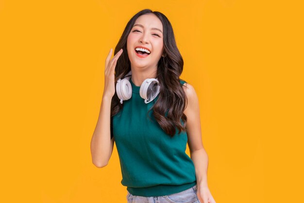 Happiness carefree asian female woman teen wearing headphone listen dance joyful fun moving moment teen wear casaul cloth singing move while laugh smile trendy lifestyle studio shot