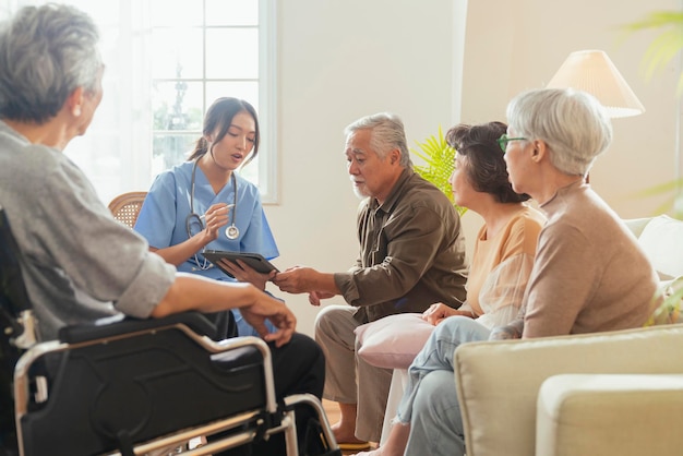 Happiness Cheerful elderly woman and men talking with female caregiver nurse doctor having health checking consult at living areaCaretakers with senior couple sitting in living room at nursing home