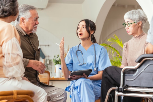 幸福元気な年配の女性と男性がリビングエリアで健康診断相談を受けている女性介護者看護師医師と話しているナーシングホームのリビングルームに座っている老夫婦との介護者