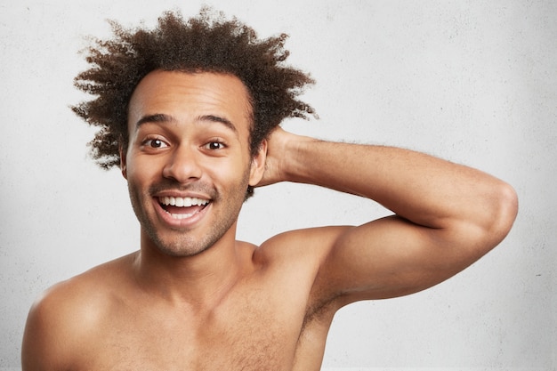 Happiness concept. Glad positive Afro American man with trendy hairstyle poses naked