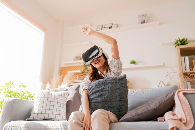 Happiness exited asian female teen hand wave along with her virtual concert performance via virtual goggle virtual interactive headsetasia woman stay home innovation technology lifestyle vr at home