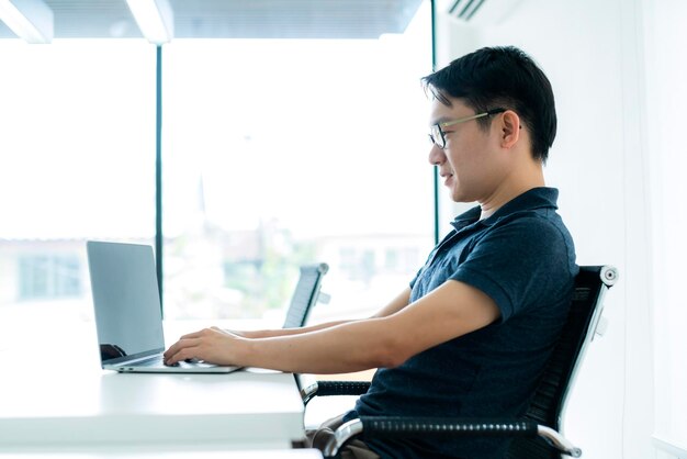 Happiness glasses asian man work hand use laptop at home with smile and energy white room background