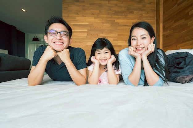 Free photo happiness joyful asian family mom dad daughter laydown together with fun play kiss on bed portrait of asian family people home background