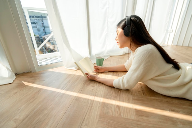 Happiness and peaceful asian woman enjoy melody and book weekend house background