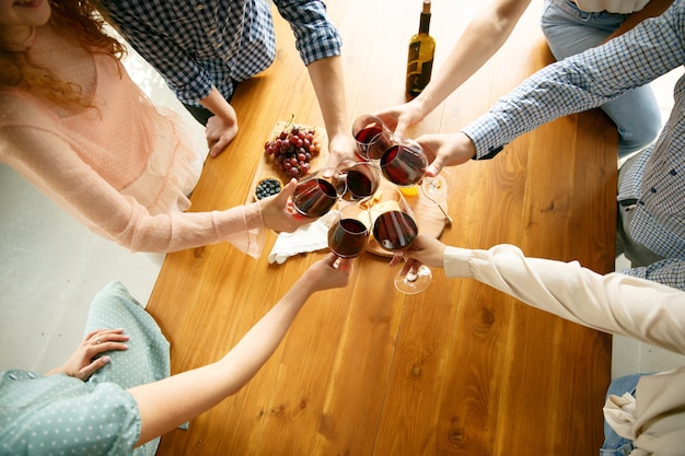 Felicità. persone che tintinnano bicchieri di vino o champagne.