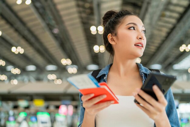 Happiness smiling asian adult female wear casual cloth hand gesture showing passport and blank screen smartphone at aitport terminalasian female ready to travel after lockdown is over at airport