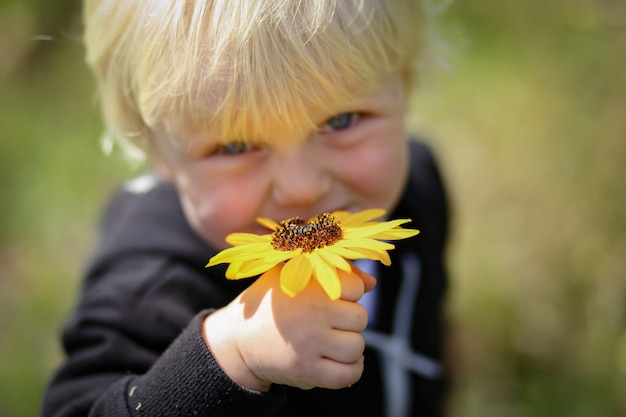 Happy adorable blonde Australian kid holding a yellow flower