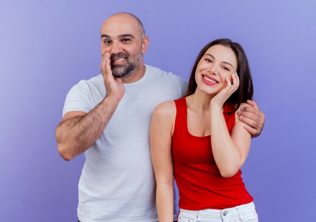 Happy adult couple both looking and touching face and man putting hand on woman's shoulder 