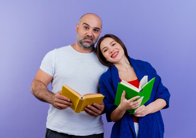 本を持っていると見ている両方のショールに包まれた幸せな大人のカップルの女性